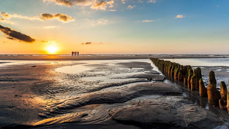 Sunset over mudflat with hiking group on the horizon. Janis Meyer/Waddenagenda.